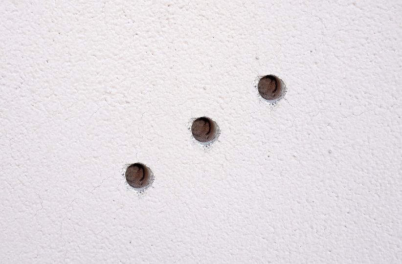 Zbliżenie na uszkodzoną ścianę z dziurą w tynku – przykład powierzchni do naprawy