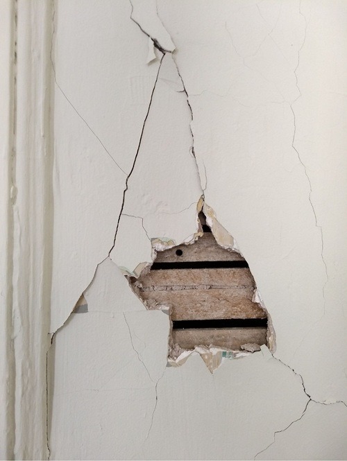 Pęknięcia i ubytki w tynku na ścianie – przykład powierzchni wymagającej naprawy masą szpachlową